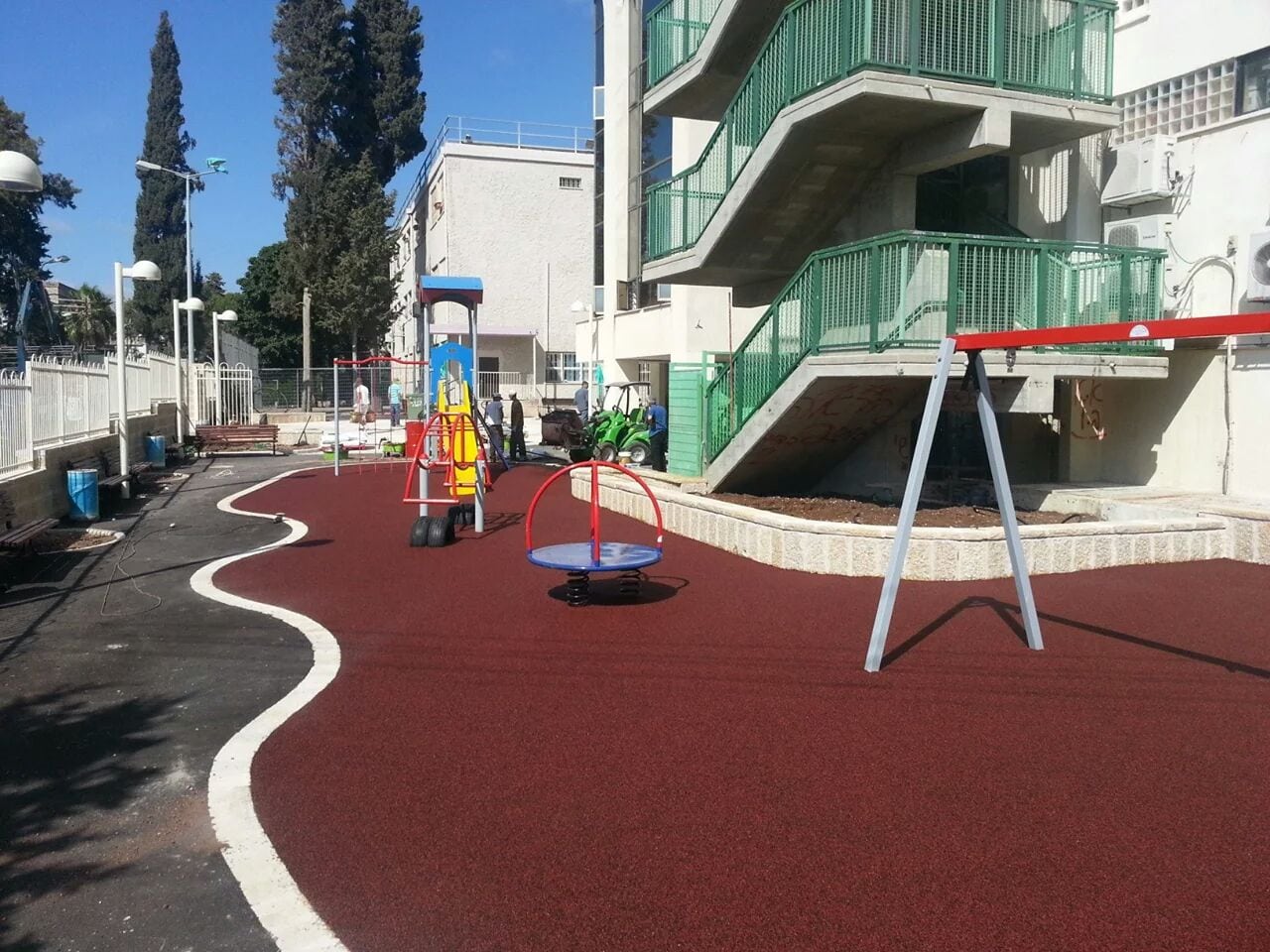 משטח גומי בגוון אדום סביב מתקני חצר